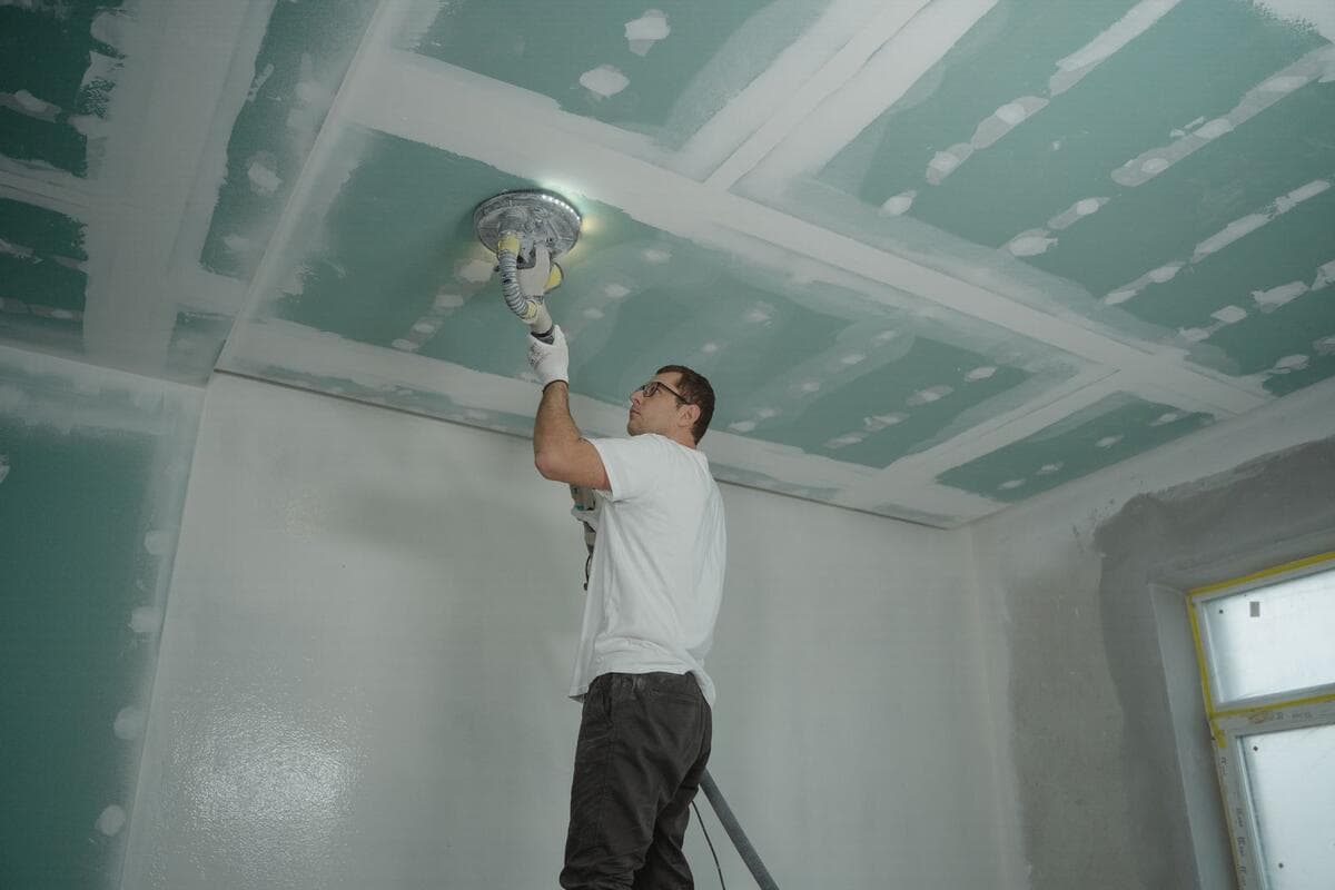 Profissional trabalhando no teto de uma casa durante reforma