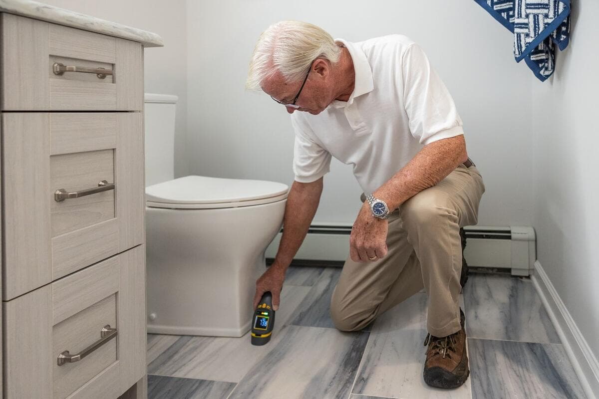 Testes que você pode fazer em casa Homem inspecionando a parte de baixo de um vaso sanitário com um aparelho