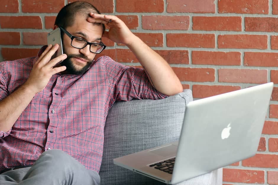 Homem sentado no sofá falando ao telefone