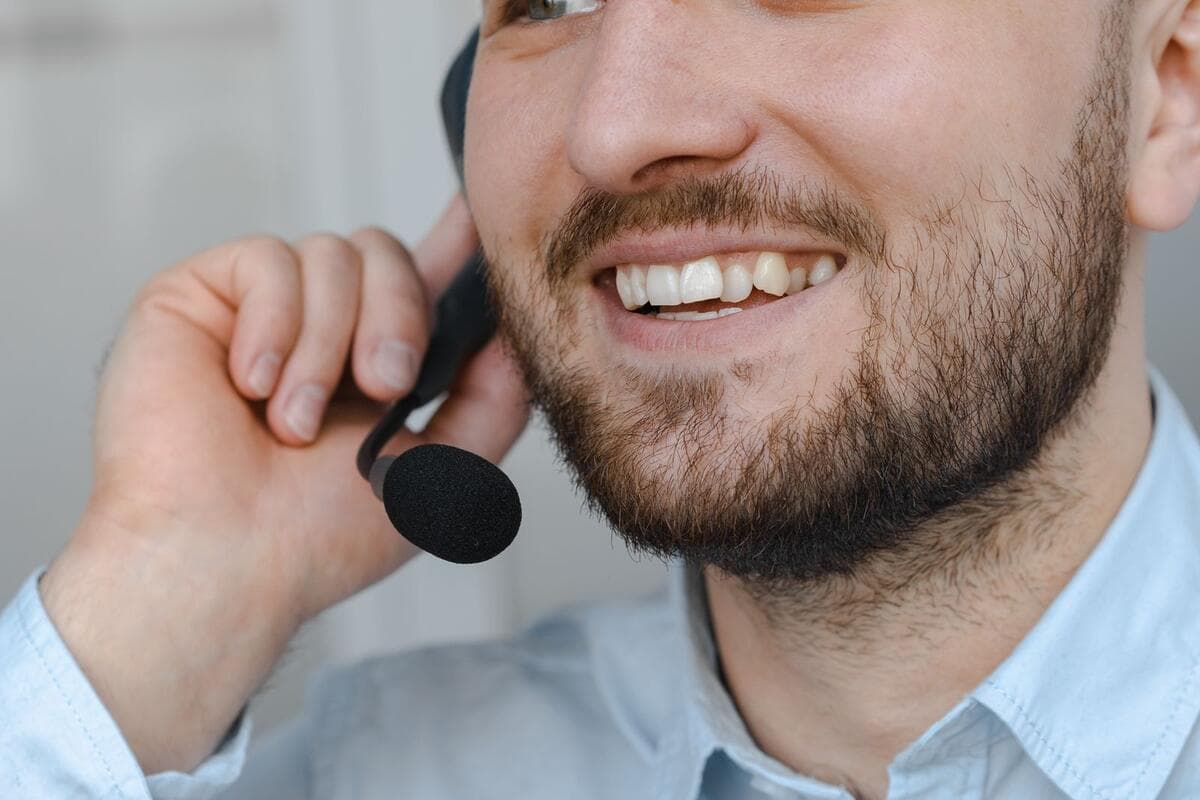 Defeito, combinado ou expectativa? Atendente sorrindo durante uma ligação com fone e microfone