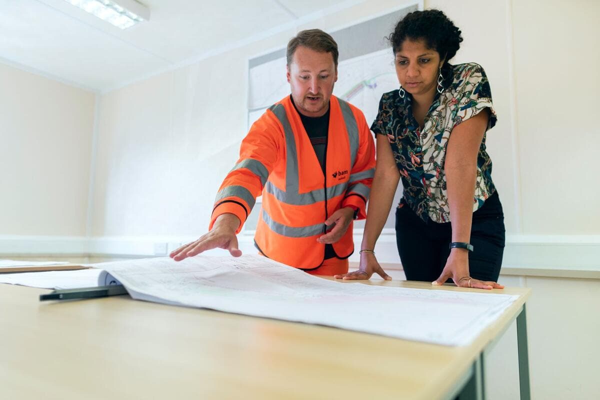 Quando não ceder e como transformar a reclamação em indicação Profissional de obra e cliente revisando juntos o projeto em uma mesa