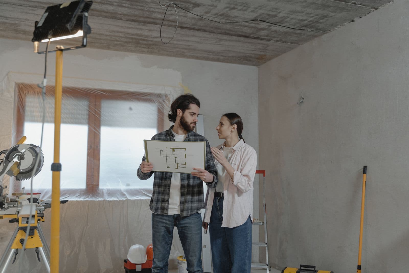 Casal analisando a planta de um cômodo em reforma Casal analisando a planta de um cômodo em reforma