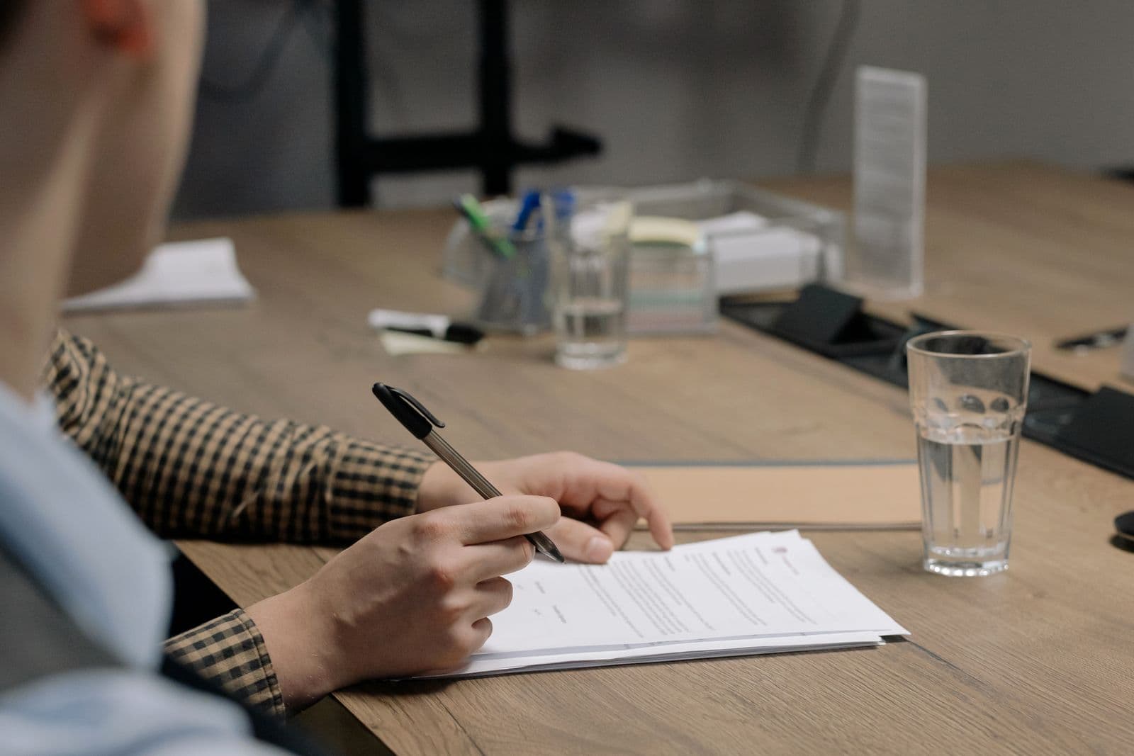 Pessoa assinando um orçamento de reforma em uma mesa de madeira