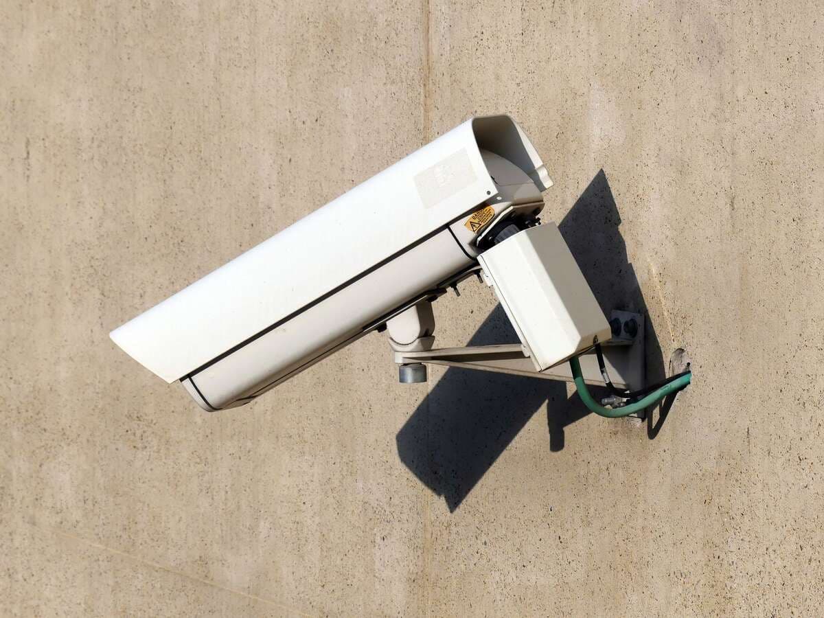 Câmera de segurança branca instalada em uma parede bege