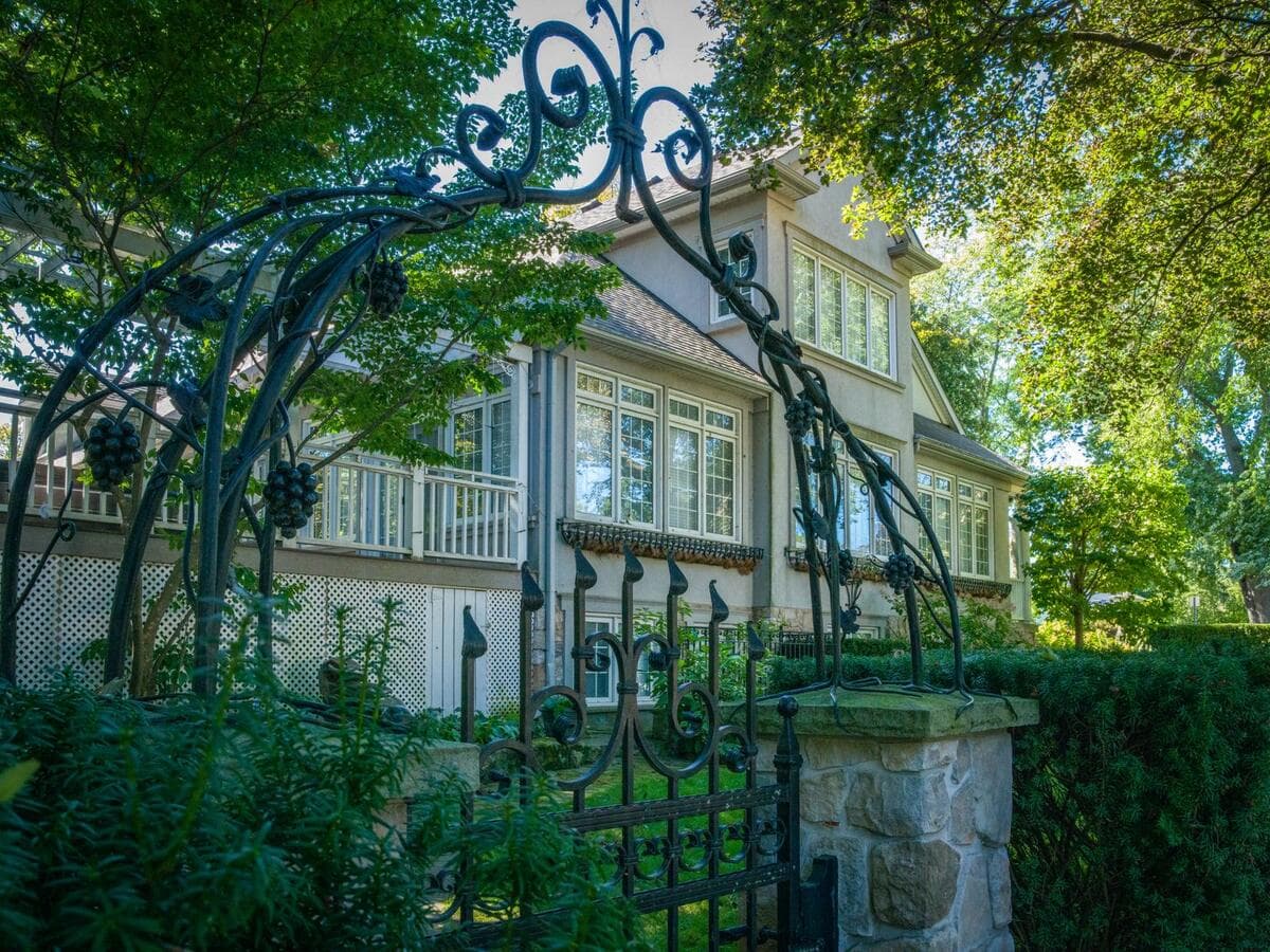 O que pedir no orçamento Portão de ferro ornamentado na entrada de uma casa com jardim