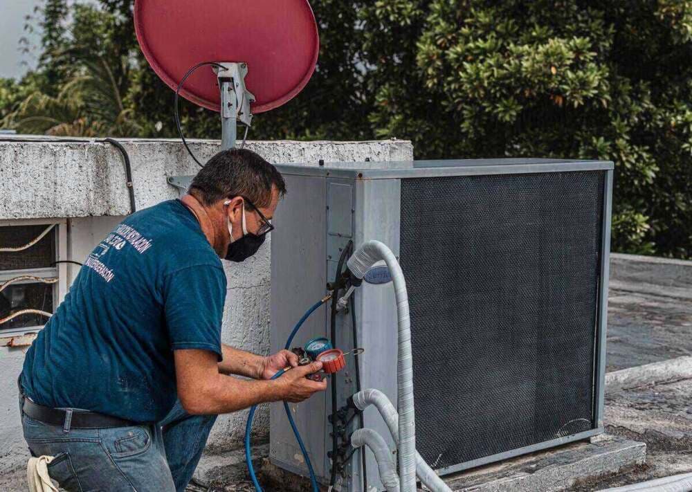 Técnico de refrigeração medindo a pressão do ar-condicionado com manifold durante manutenção