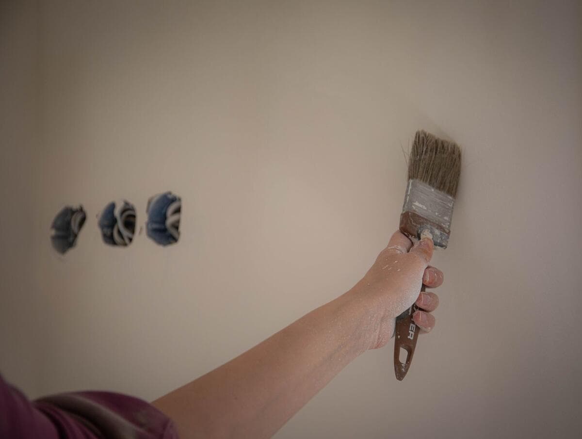 Durante e depois do serviço: o que conferir Pessoa pintando parede com pincel em reforma de casa