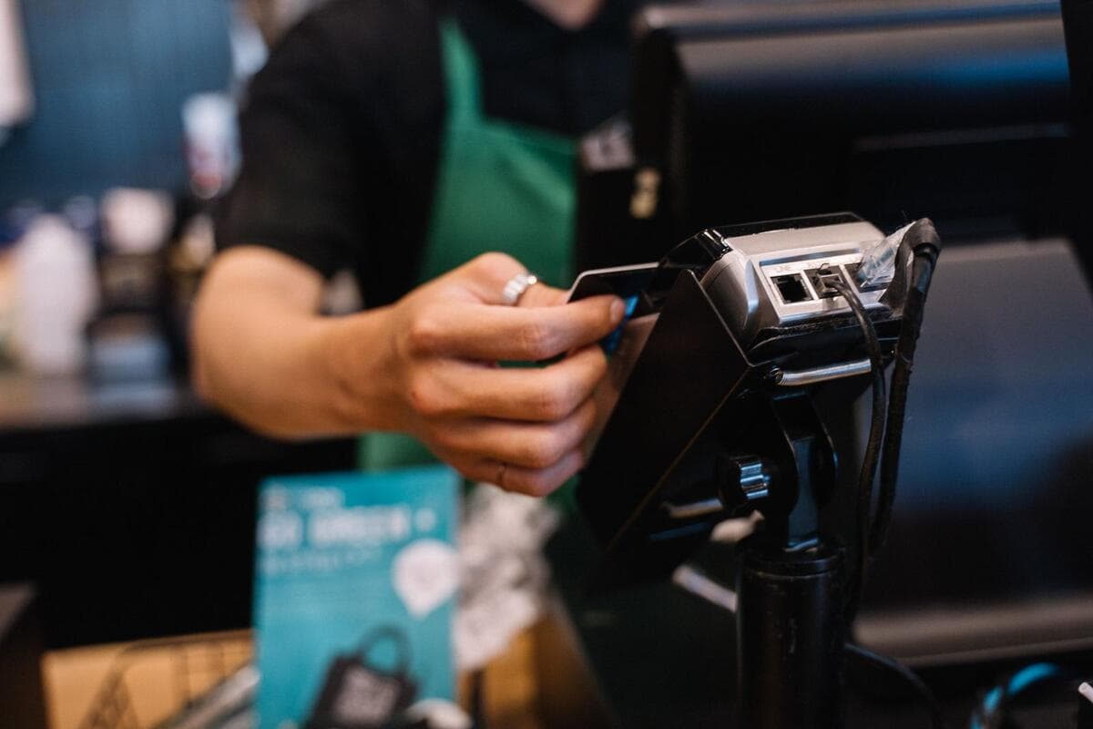 Cliente pagando com cartão na maquininha em um balcão