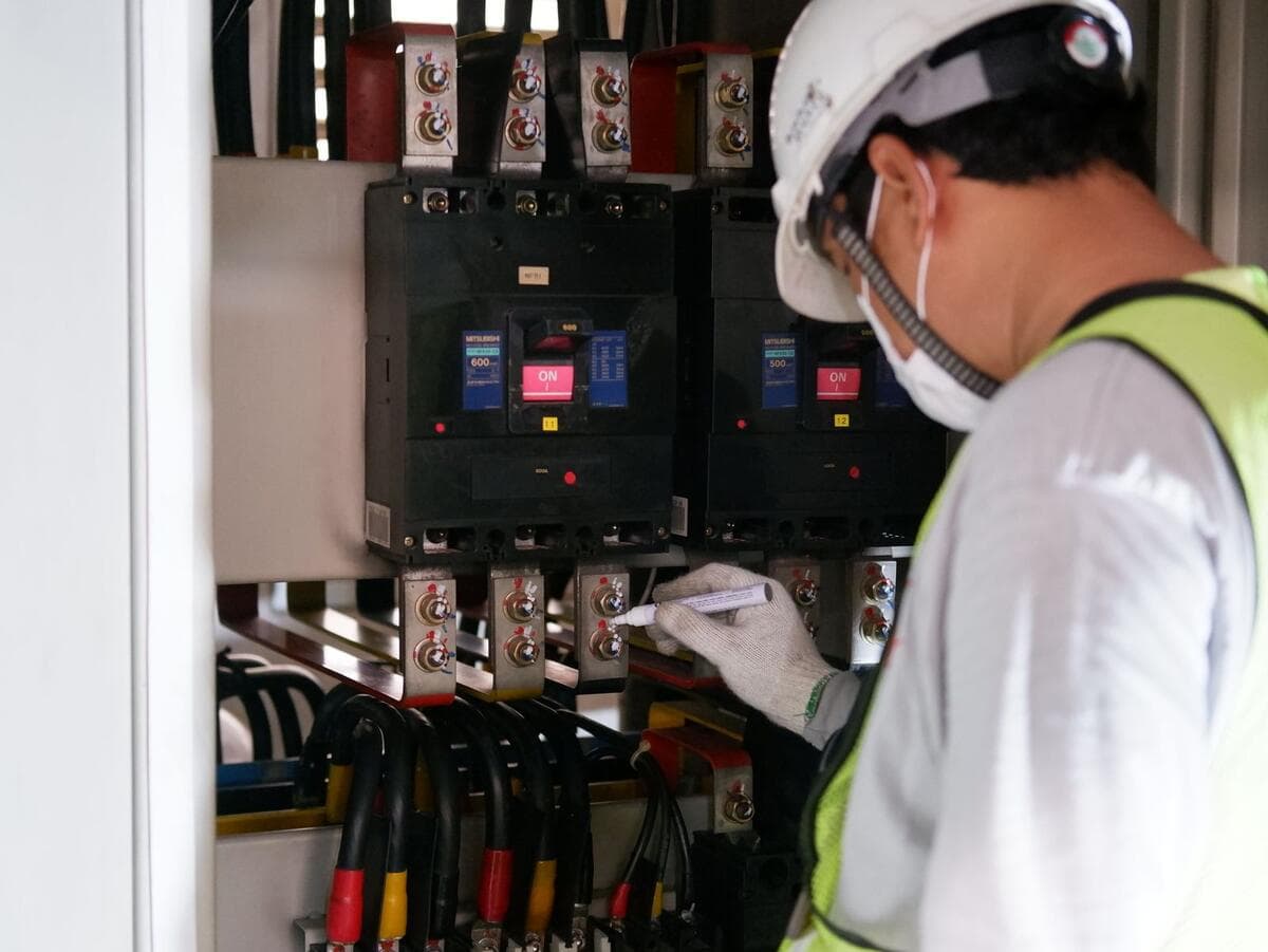 Técnico com equipamento de segurança inspecionando quadro elétrico