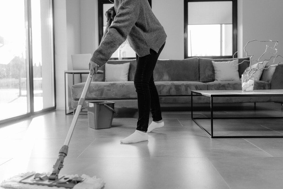 Quanto custa a limpeza pós-obra Pessoa passando mop no piso de uma sala moderna