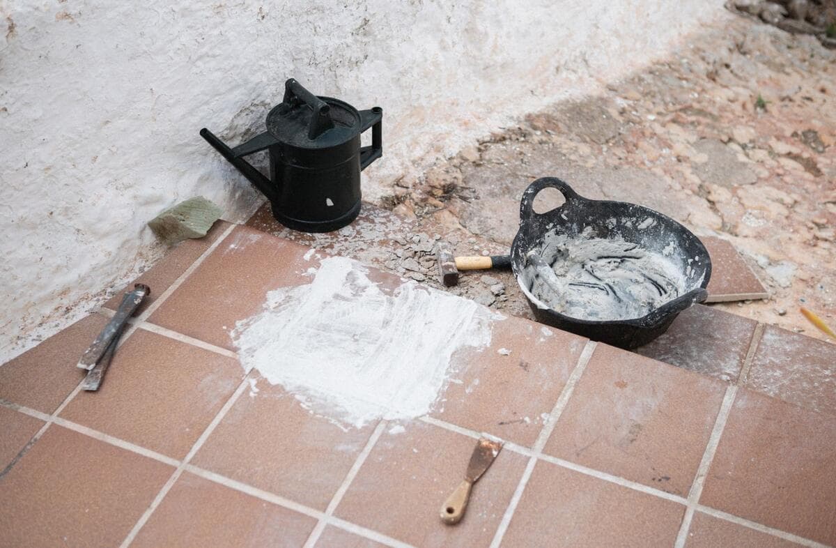 Por que a goteira nem sempre está onde aparece Ferramentas e material de obra sobre piso de cerâmica durante um reparo