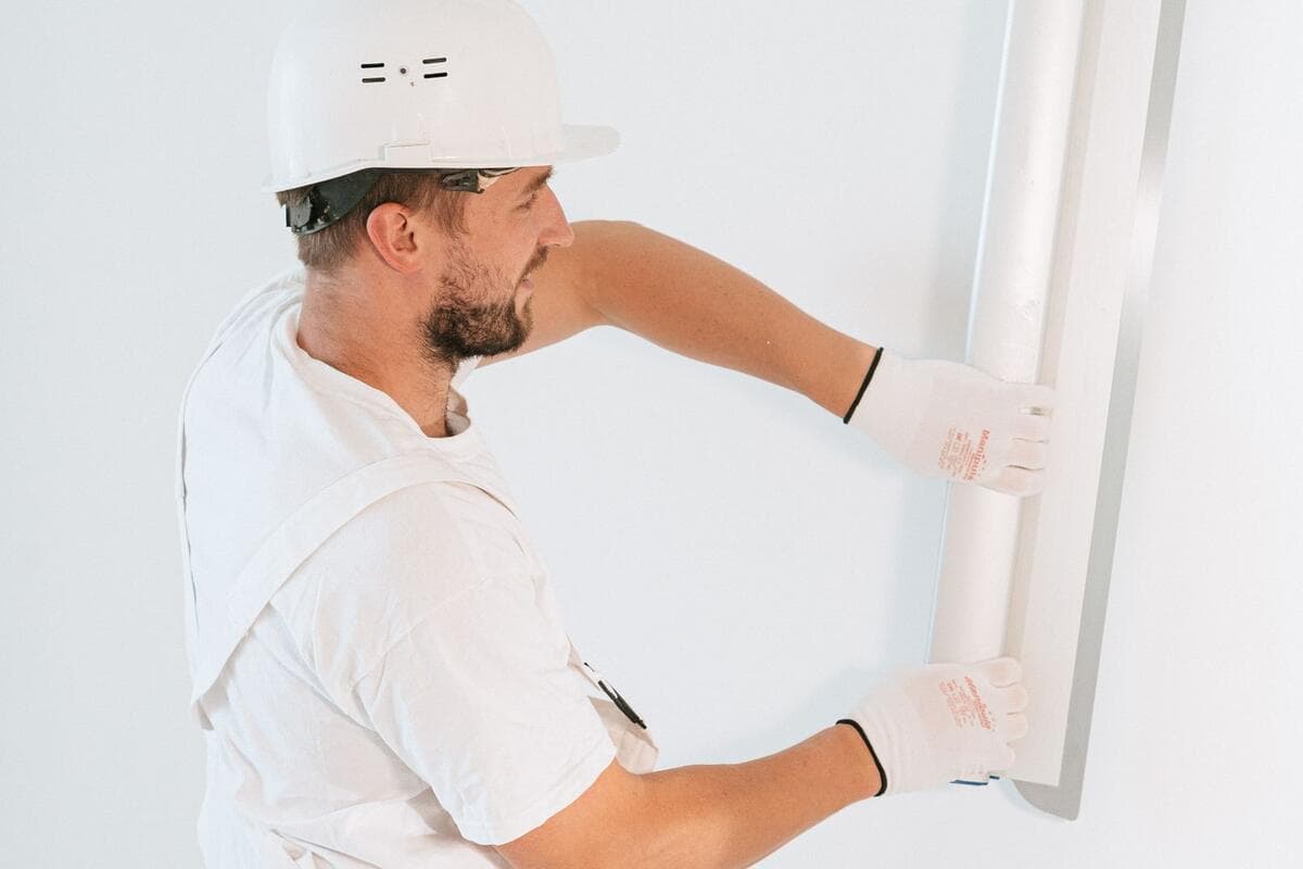 Profissional de capacete e luvas instalando placas de drywall