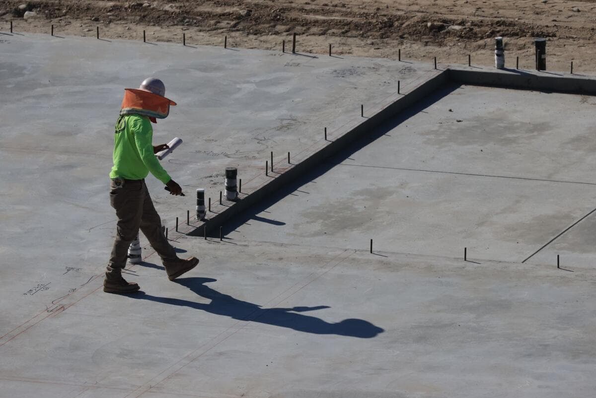 O que um bom serviço de impermeabilização inclui Engenheiro inspecionando uma laje de concreto na obra