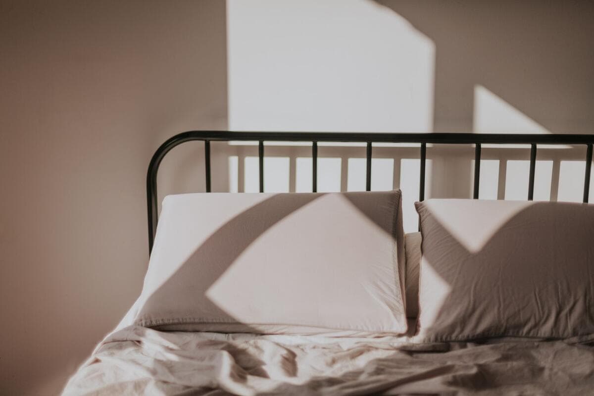 O que faz o preço subir ou cair Cama com travesseiros e lençóis iluminada pelo sol da manhã