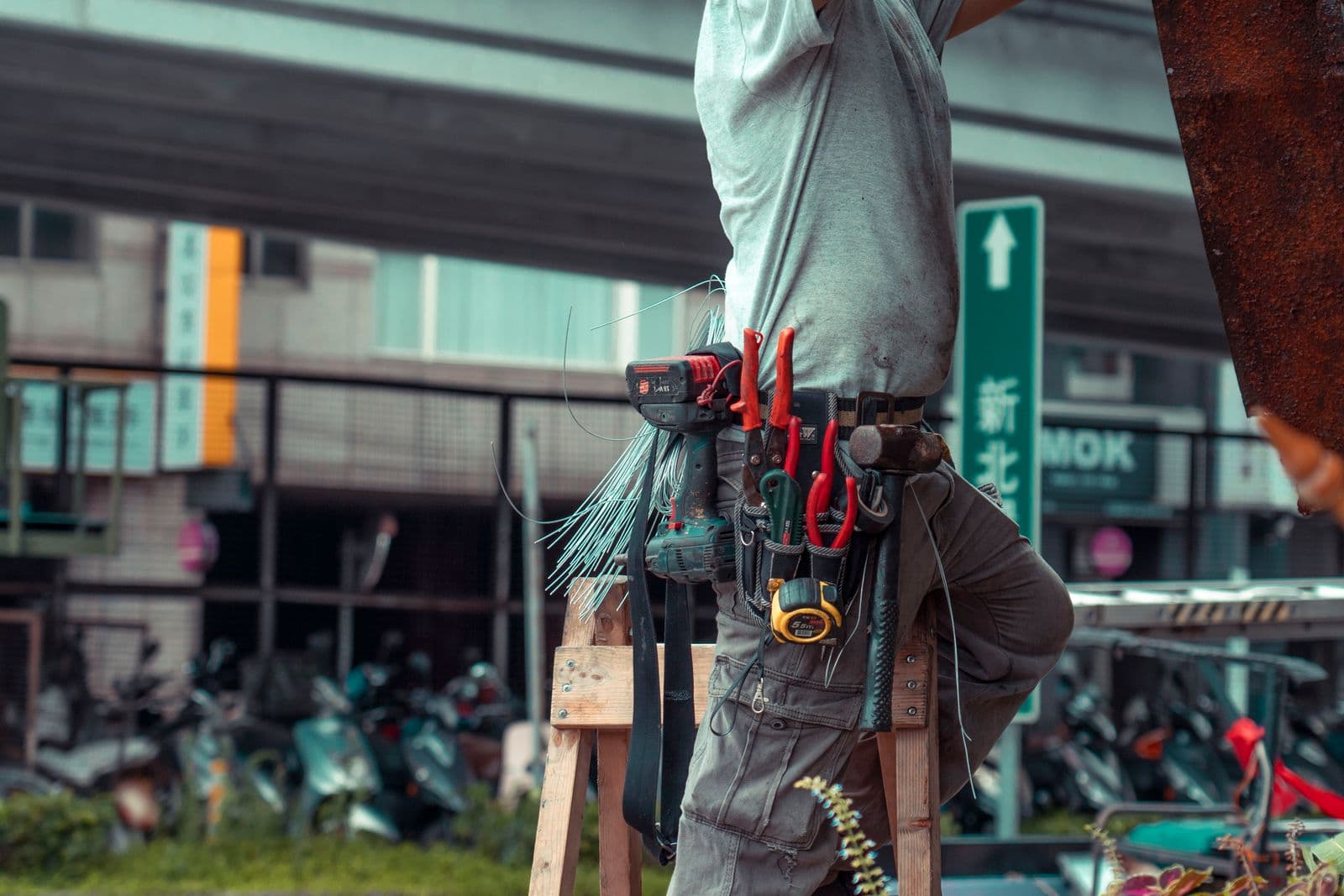 Profissional de pequenos reparos com cinto de ferramentas trabalhando em uma escada Profissional de pequenos reparos com cinto de ferramentas trabalhando em uma escada