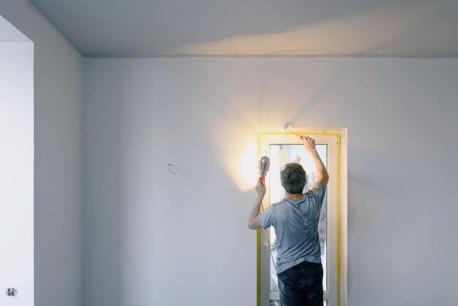 Profissional de costas reparando o batente de uma porta com uma lâmpada acesa